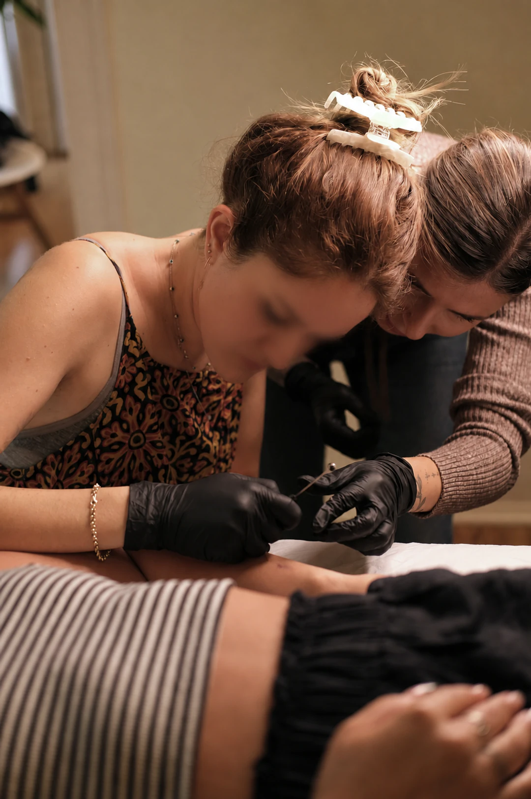 Maria Pokes mentoring a handpoke tattoo student during a practical workshop in Lisbon